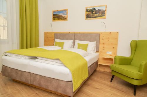 een slaapkamer met een bed en een groene stoel bij Landhotel Moshammer in Waidhofen an der Ybbs