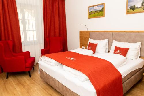 a bedroom with a red bed and a red chair at Landhotel Moshammer in Waidhofen an der Ybbs