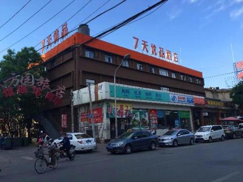 a building with cars and people on motorcycles on a street at 7Days Premium Beijing Fengtai South Road Subway Station Wumei Market Branch in Beijing