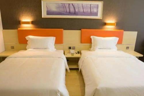 two beds in a room with white sheets and orange headboards at 7Days Premium Beijing Fengtai South Road Subway Station Wumei Market Branch in Beijing