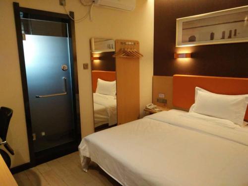 um quarto de hotel com uma cama e uma porta para um quarto em 7Days Premium Wuzhong Wanda Plaza Branch em Wuzhong