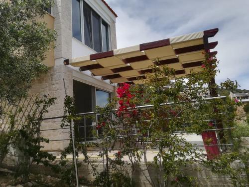 a house with a balcony with flowers on it at Stone House in olive grove in Tolo