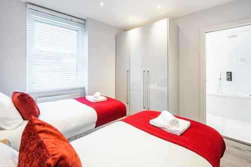2 Betten in einem weißen Zimmer mit roten Decken in der Unterkunft Cozy and Serene brand-new flat in Kilburn, London in London