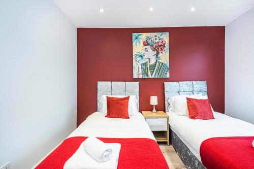 2 Betten in einem Zimmer mit roten Wänden in der Unterkunft Cozy and Serene brand-new flat in Kilburn, London in London