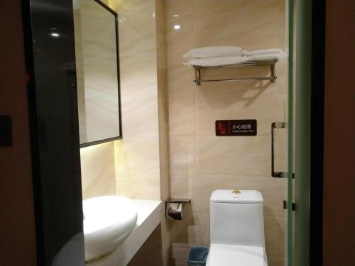 uma casa de banho com um lavatório branco e um WC. em 7Days Premium Chongqing Qijiang District Government Branch em Qijiang