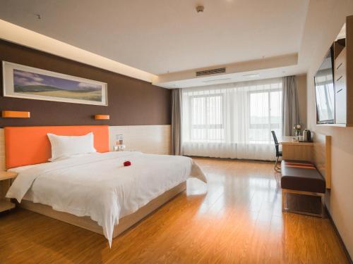 ein Schlafzimmer mit einem großen weißen Bett und einer orangefarbenen Wand in der Unterkunft 7Days Premium Chongqing Baishiyi Hot Spring Capital Branch in Chongqing