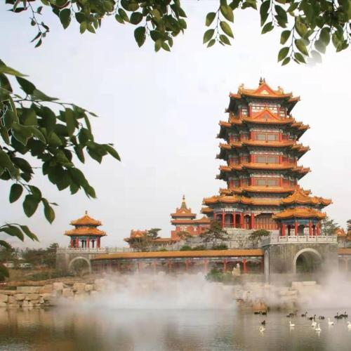 a chinese building in the middle of a lake with ducks at 7Days Premium Yantai Penglai New Bus Station Branch in Penglai