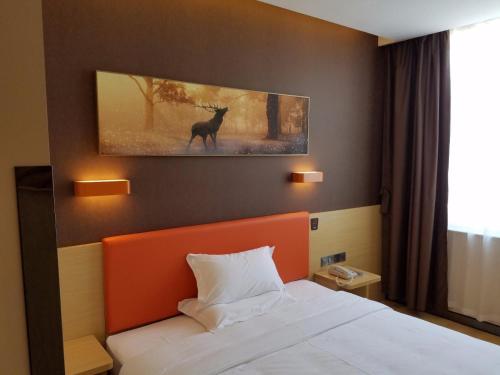 a bedroom with a bed and a painting of a deer at 7Days Premium Yantai Penglai New Bus Station Branch in Penglai