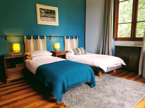 a bedroom with two beds and a blue wall at Villa Gracieuse in Luchon