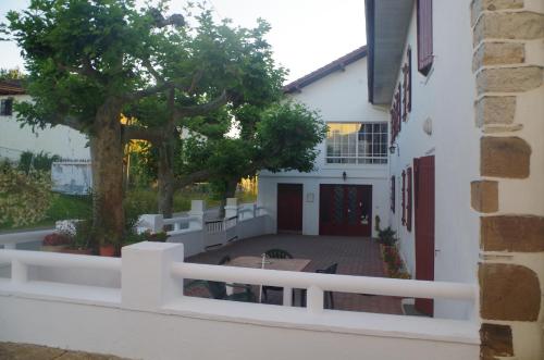 a white building with a tree and a white fence at Maison Elizondoa - chambres, restaurant et SPA in Masparraute