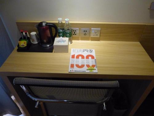 a desk with a coffee maker and a book on it at 7Days Premium Delingha Center Plaza Branch in Delingha