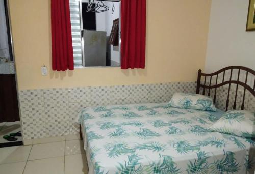 Schlafzimmer mit einem Bett, einem Spiegel und roten Vorhängen in der Unterkunft Suíte 10 com wifi a 4 min da praia em Caraguá in Caraguatatuba