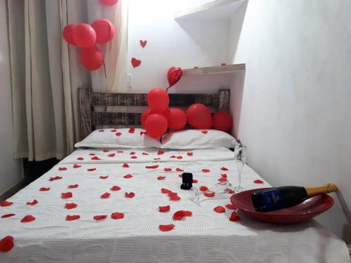 Ein Bett mit roten Ballons und einem Haufen Herzen in der Unterkunft Suíte 3 com wifi a 4 min da praia em Caraguatatuba in Caraguatatuba