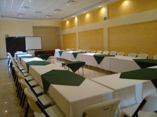 a conference room with tables and chairs and a screen at Hotel Las Fuentes in Los Mochis