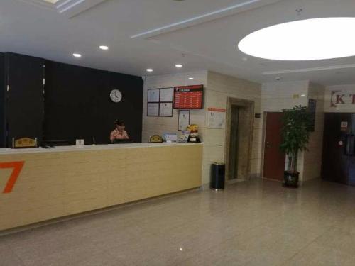 a lobby with a counter and a woman sitting at a counter at 7Days Premium Yi'ning Shanghaicheng Branch in Kipekyüzi