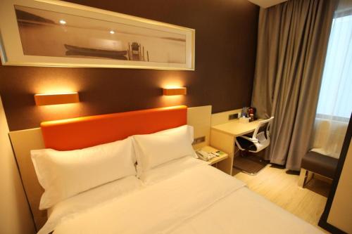 a bedroom with a bed with an orange headboard and a desk at 7Days Premium Harbin Xuefu Road Branch in Harbin