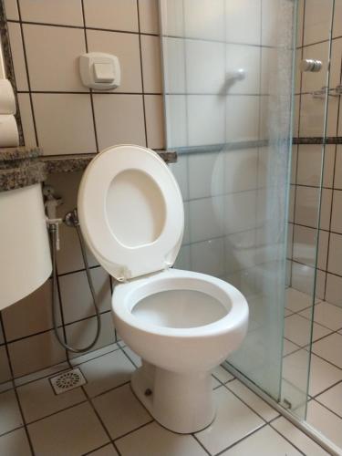 a bathroom with a toilet and a glass shower at diRoma Fiori - Apartamentos JN in Caldas Novas