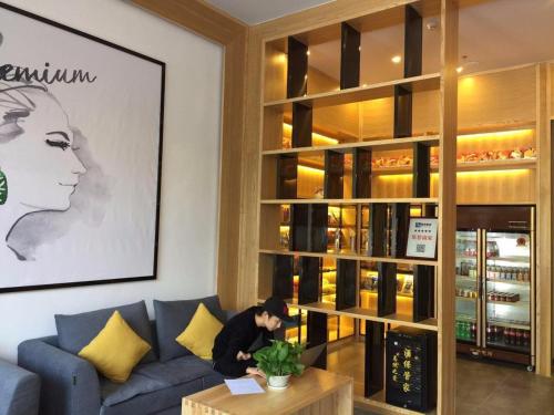 a man sitting on a blue couch in a living room at 7Days Premium Yichang Wanda Plaza Canal Park Branch in Yichang