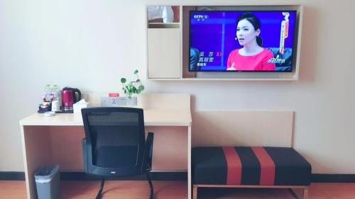 a room with a desk and a tv on the wall at 7Days Premium Suqian Yanghe Town Branch in Suqian