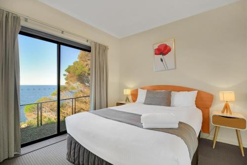 a bedroom with a large bed and a large window at Eagle Heights Holiday Units in Eden