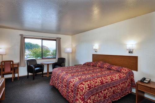 a hotel room with a bed and a desk and a window at Cap Sante Inn in Anacortes