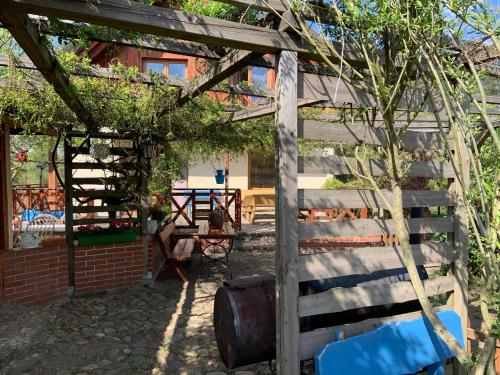 a wooden pergola in a yard next to a house at Zakątek RąbÓwka Dom Ryby Bania in Rąb