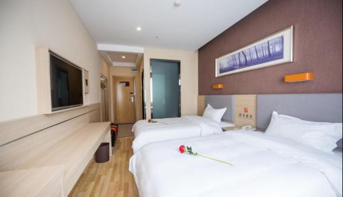 um quarto de hotel com duas camas e uma televisão de ecrã plano em 7Days Premium Kunming University Town Subway Station Branch em Huacheng