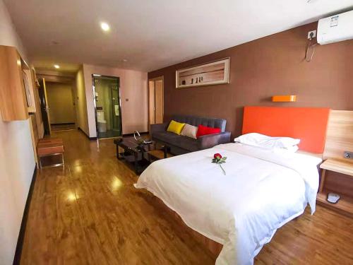 a bedroom with a large white bed and a couch at 7Days Premium Chengde University City High Speed Rail Station Branch in Chengde