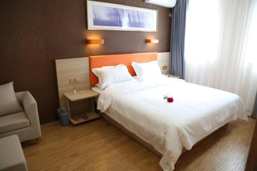 Un dormitorio con una cama blanca con una flor roja. en 7Days Premium Yancheng Dafeng Zhongjiao Meilucheng Branch, en Yancheng