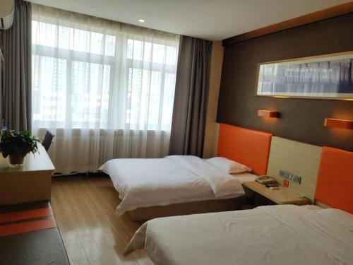 a hotel room with two beds and a window at 7Days Premium Dingxi Train Station Branch in Dingxi