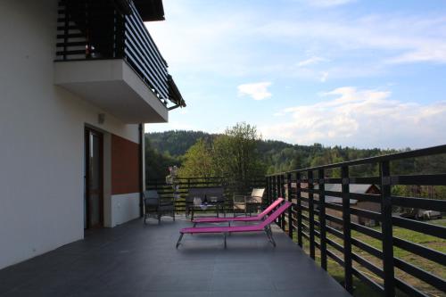 a balcony with two pink chairs and a table at Dom w Milówce - Apartamenty na Kowolu in Milówka