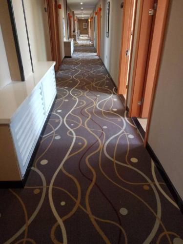 a hallway of an office building with a carpet with swirl patterns at 7Days Premium Heihe Nenjiang County Keyun Station Branch in Nenjiang