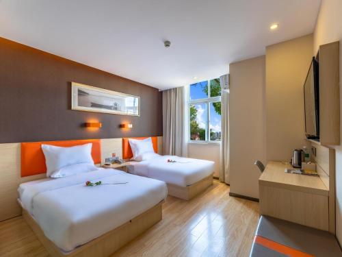 a hotel room with two beds and a television at 7Days Premium Xichang Torch Plaza Qionghai Wetland Park Branch in Xichang