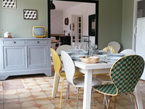 Un comedor con una mesa y sillas blancas. en Propriété de charme-6 pers Le Pouldu, en Clohars-Carnoët