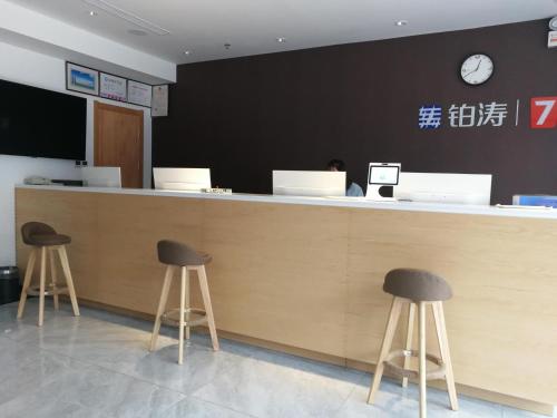 a lobby with a counter with two stools in front at 7Days Premium Anyang Tangyin Yuefei Temple Branch in Anyang