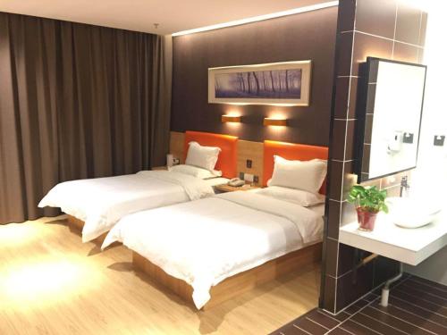 a hotel room with two beds and a mirror at 7Days Premium Anyang Tangyin Yuefei Temple Branch in Anyang