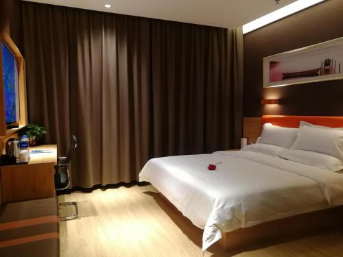 a bedroom with a large white bed with a red rose on it at 7Days Premium Anyang Tangyin Yuefei Temple Branch in Anyang