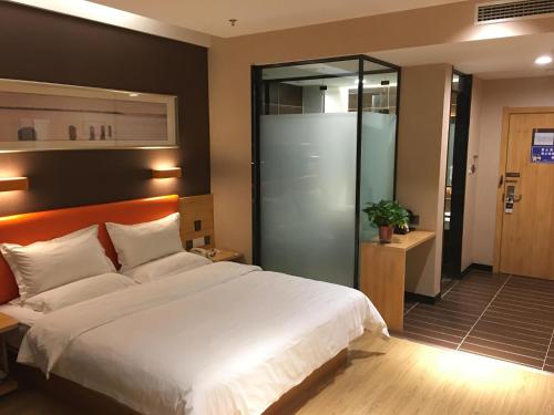 a bedroom with a large white bed and a glass door at 7Days Premium Anyang Tangyin Yuefei Temple Branch in Anyang