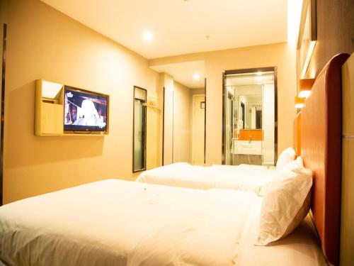 a hotel room with two beds and a tv at 7Days Premium Fuzhou Dongxiang High Speed Railway Station Branch in Fuzhou