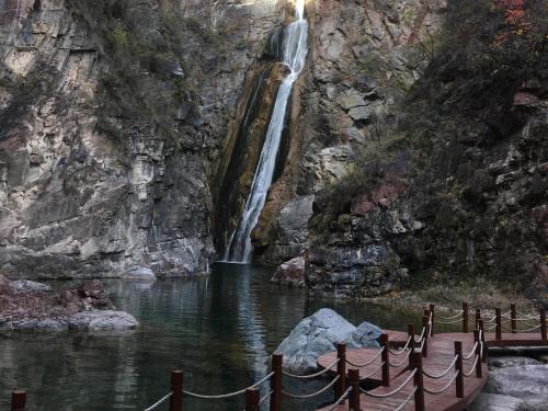a waterfall in a canyon with a boat in the water at 7Days Premium Shiyan Renmin Road Sanyan Coach Station Branch in Shiyan