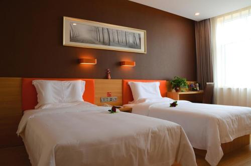 ein Hotelzimmer mit 2 Betten und einem Bild an der Wand in der Unterkunft 7Days Premium Shijiazhuang Zhonghua Avenue North 2nd Ring Mingyue Jiaju Branch in Shijiazhuang