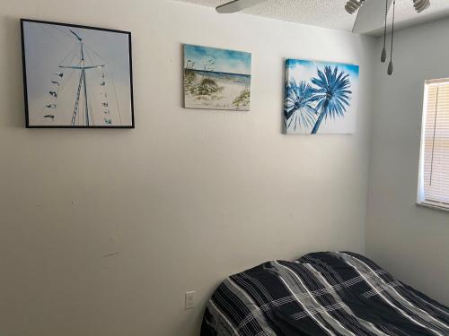 a bedroom with three pictures on the wall at Private room in a 2 bedroom 1 bathroom shared with host, on the beach, surrounded by resorts, only 2 people MAX in St Pete Beach