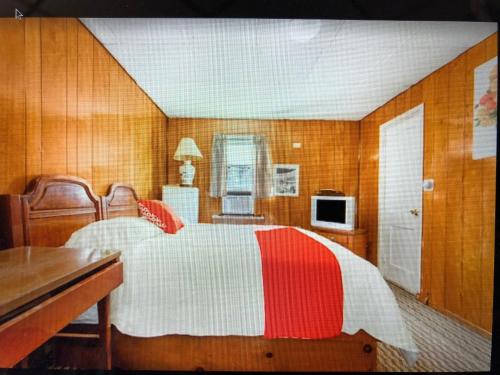 sypialnia z łóżkiem z czerwonym i białym kocem w obiekcie Monmouth OYO w mieście Neptune City