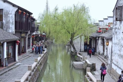 Un río en una ciudad con gente caminando por la calle en 7Days Premium Suzhou Tongli Ancient Town Branch en Suzhou