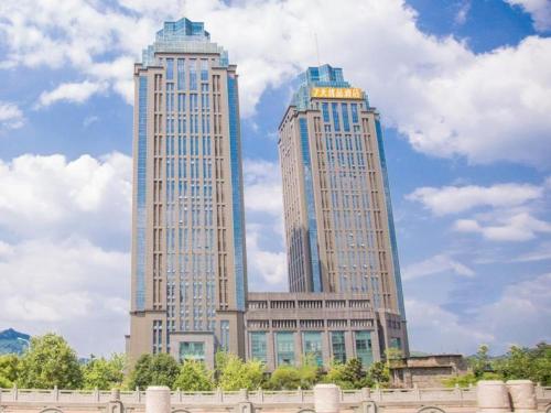 dos rascacielos altos en una ciudad con nubes en el cielo en 7Days Premium Chongqing Nanchuan Government Square Branch, en Nanchuan