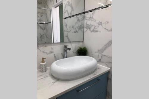 une salle de bain avec un lavabo blanc et un miroir dans l'établissement Studio cosy 30 m2 climatisé au centre ville de LGM, à La Grande Motte