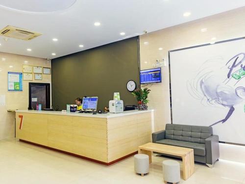 a woman sitting at a counter in an office at 7Days Premium Xiamen Airport Xianglu Branch in Xiamen