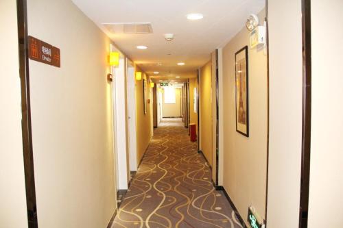 7Days Premium Haikou Pearl Plaza Wuzhishan Road Branch في هايكو: ممر في فندق مع ممر طويل