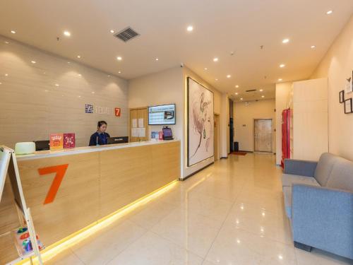 a man is standing at a counter in a waiting room at 7Days Premium Lanzhou New District Airport Branch in Lanzhou