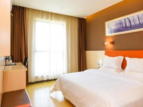 a bedroom with a large white bed and a window at 7Days Premium Lanzhou New District Airport Branch in Lanzhou